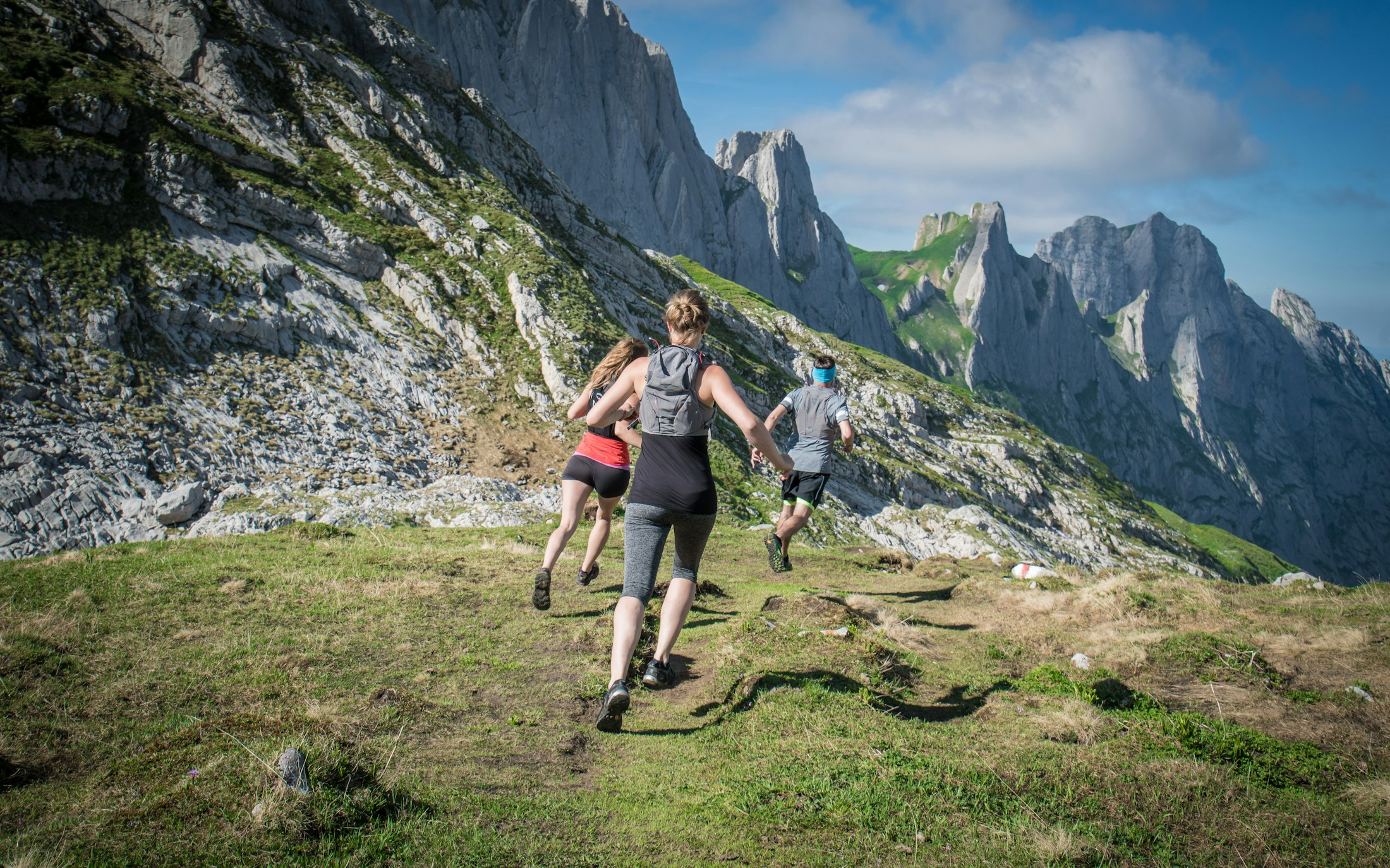 Hikers moving through a high mountain pass under cloud cover.