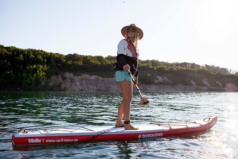 A woman paddling a stand-up paddleboard on a beautiful mountain lake.